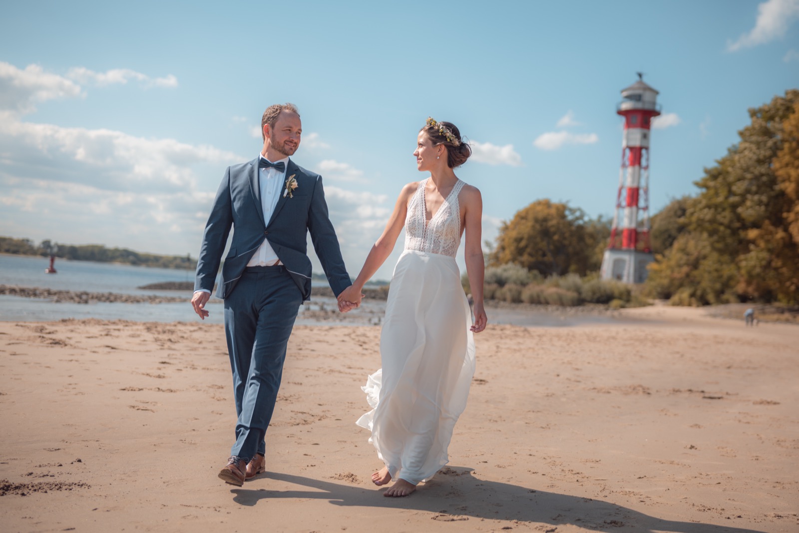 Brautpaar am Strand mit Leuchtturm im Hintergrund