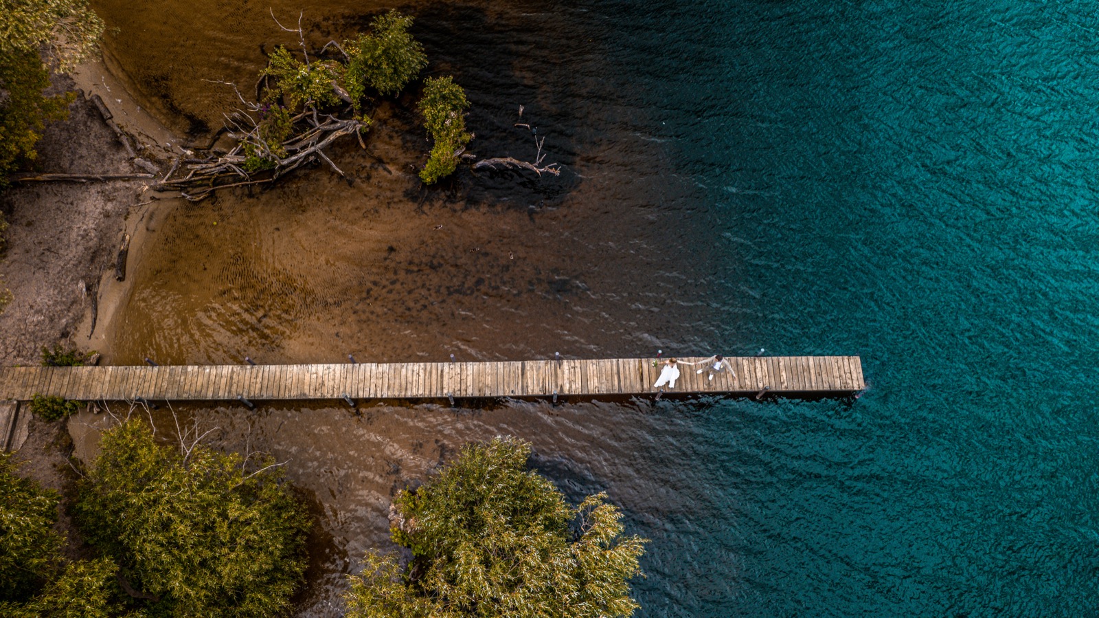 Drohnenaufnahme Brautpaar auf Holzsteg am türkisen See