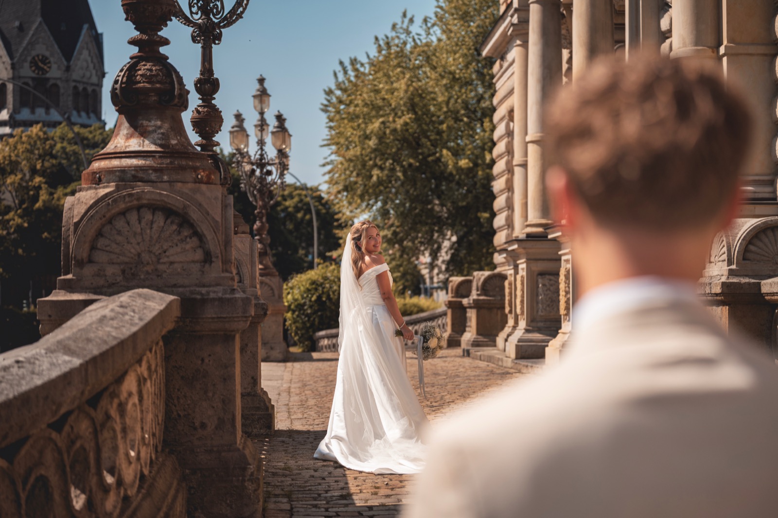 Sein Blick – Braut im Sonnenlicht, Bräutigam im Vordergrund